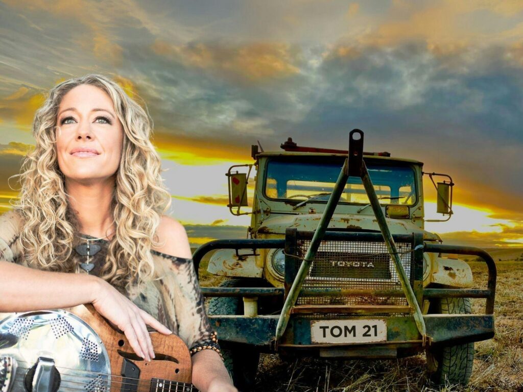 Jodi Martin and Tommy the Toyota celebrating 25 Years of Music in 2025 by saying: Never Say Die!