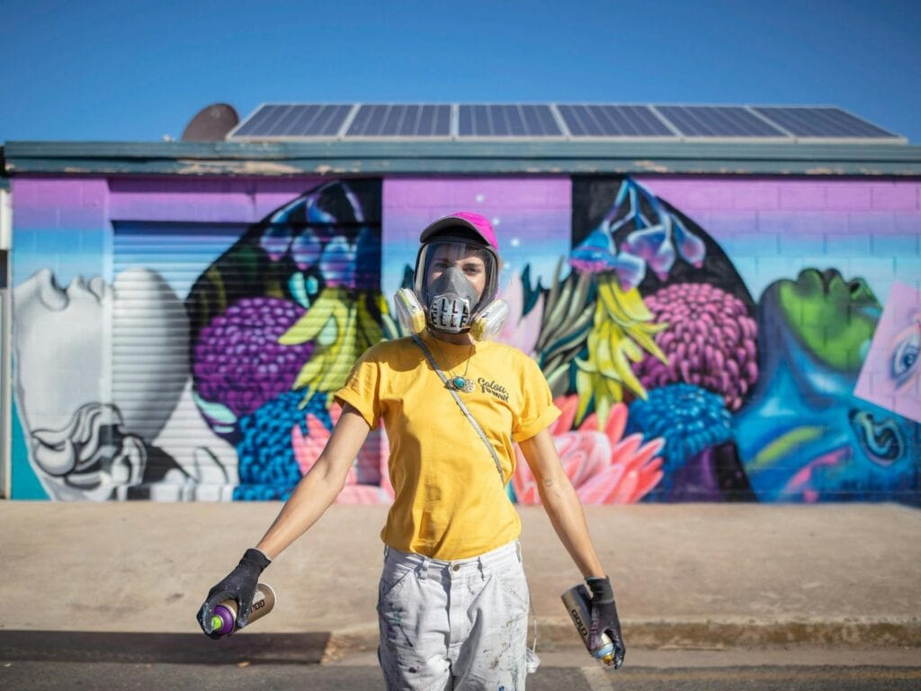 ElleStreetArt in front of her colourful collage style mural