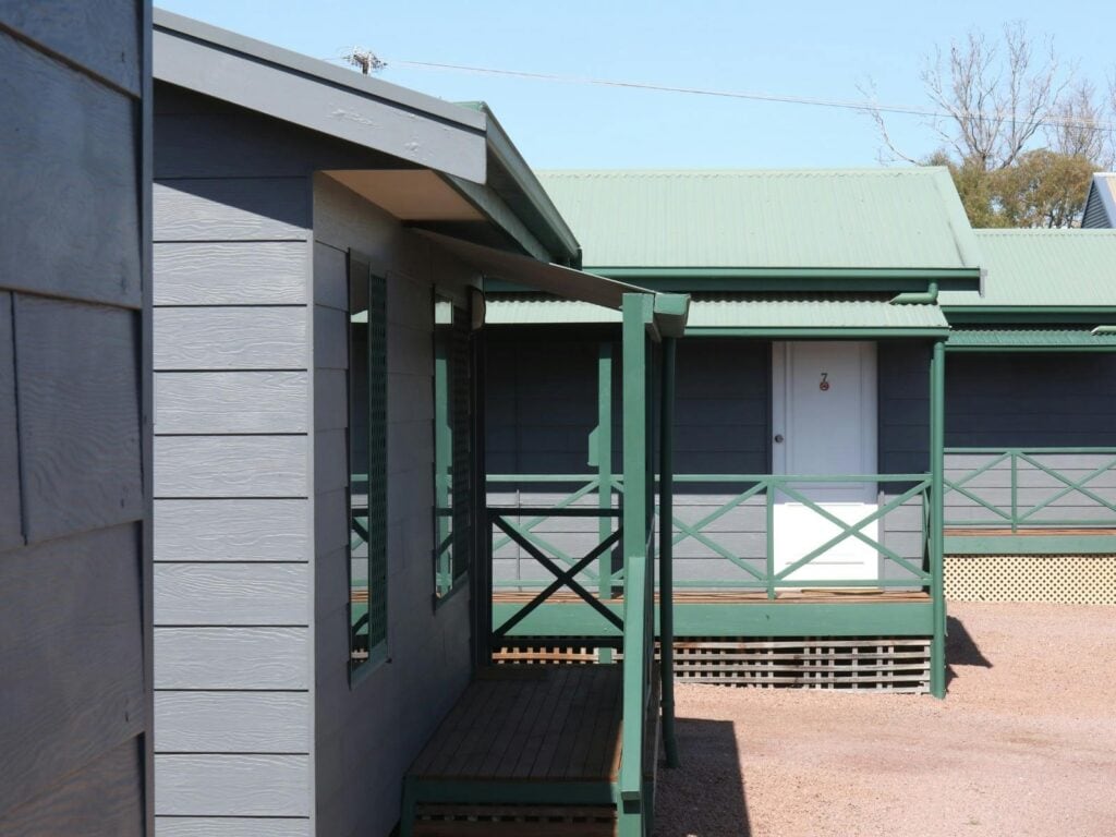 Exterior view of Port Lincoln Villas with grey painted walls, green railings and villa entrances.